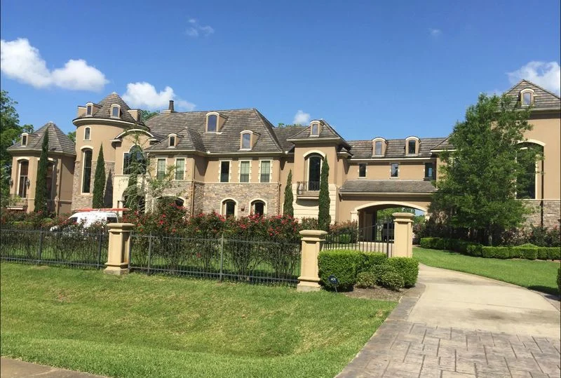Stucco home with a gated driveway and landscaped front yard